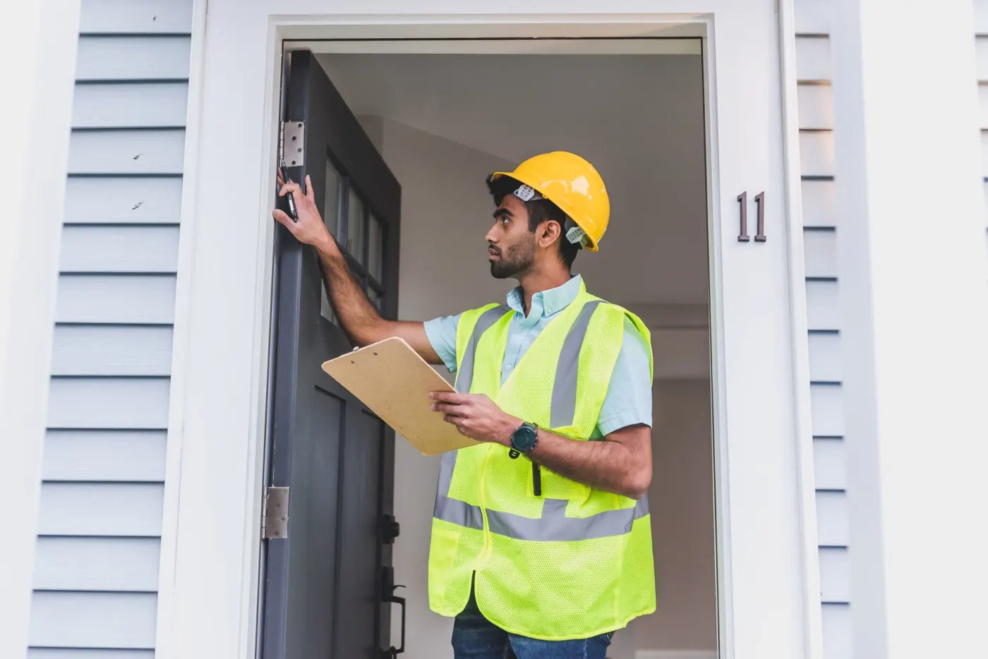 Surveyor in hi-vis checking the exterior of a home before going inside